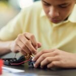 Close-up of a teenager building a robotics project, focusing on electronics and repairs.